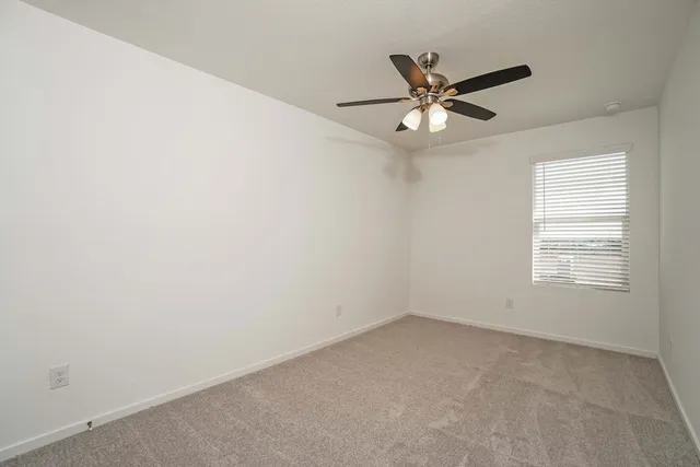 an empty room with a window and a fan
