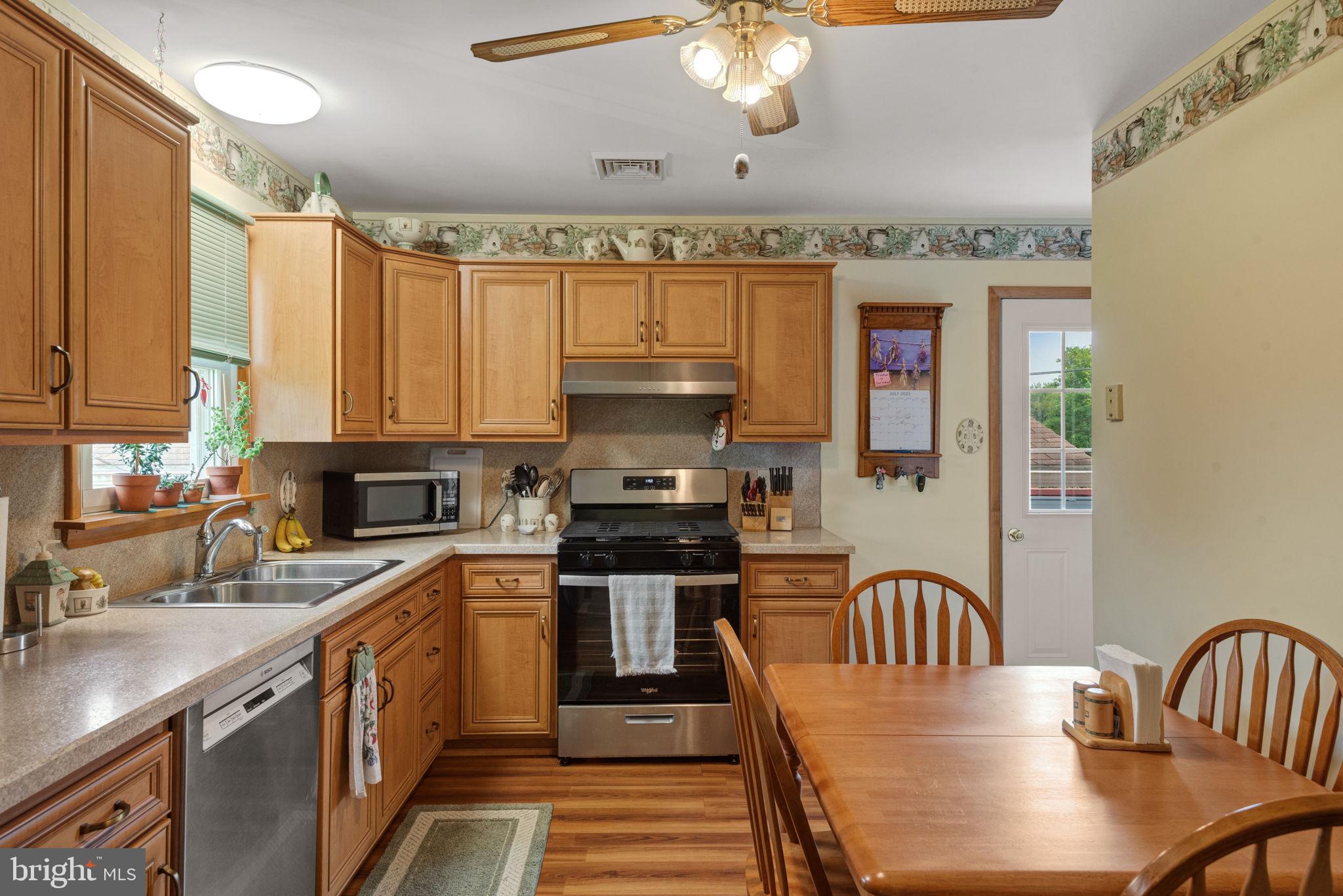4451 Pine Hill Road Dover, PA 17315 - Photo 9 of 36 a kitchen with stainless steel appliances granite countertop a stove top oven a sink dishwasher a dining table and chairs with wooden floor