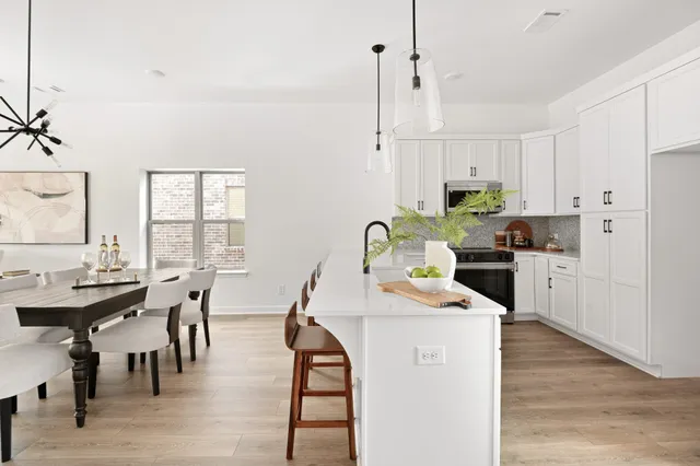 a kitchen with stainless steel appliances kitchen island granite countertop a stove a sink a dining table and chairs