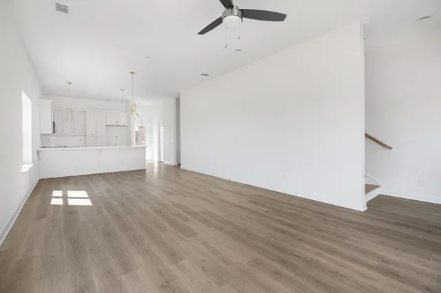 a view of a hallway with wooden floor and a bathroom