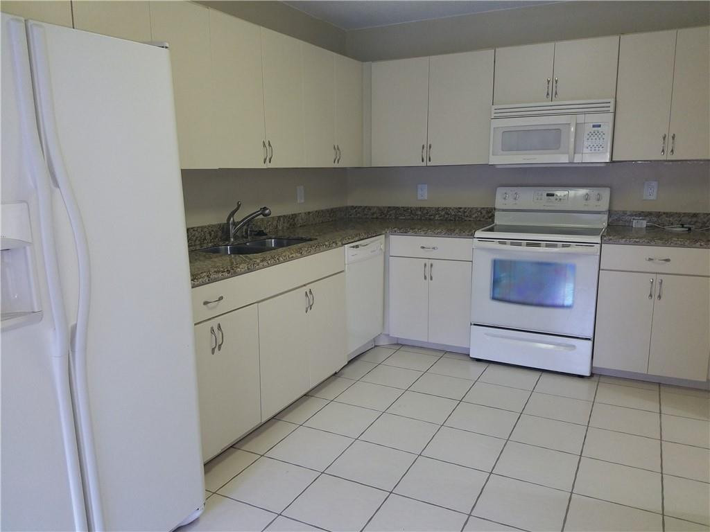 6659 Via Regina, Unit 6659 Boca Raton, FL 33433 - Photo 7 of 38 a kitchen with granite countertop white cabinets and white appliances
