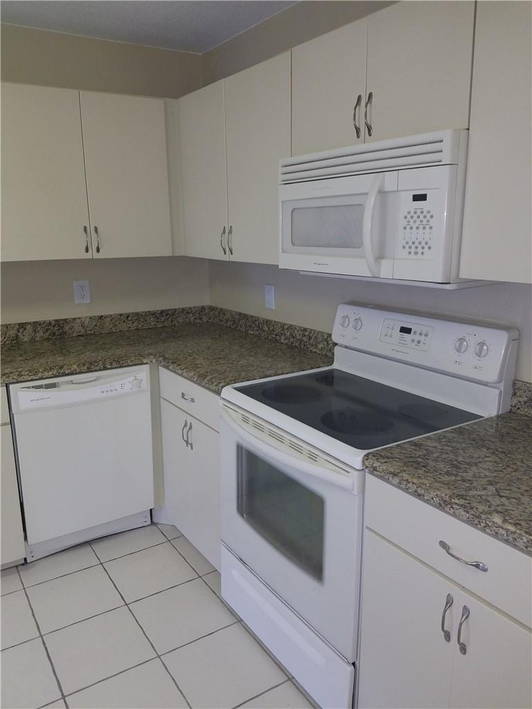 6659 Via Regina, Unit 6659 Boca Raton, FL 33433 - Photo 9 of 38 a kitchen with granite countertop white cabinets and white appliances