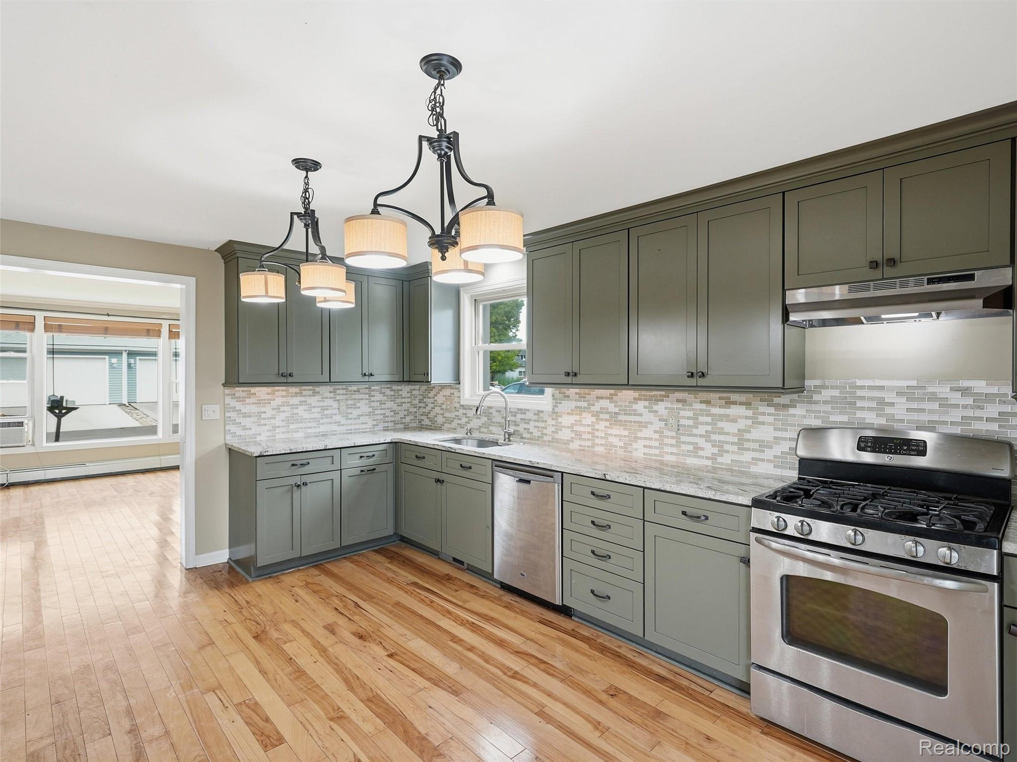 117 Kenyon Road Algonac, MI 48001 - Photo 20 of 47 Kitchen featuring wood-finish flooring, grey cabinetry with dark hardware, a mosaic tile backsplash, and light-toned countertops