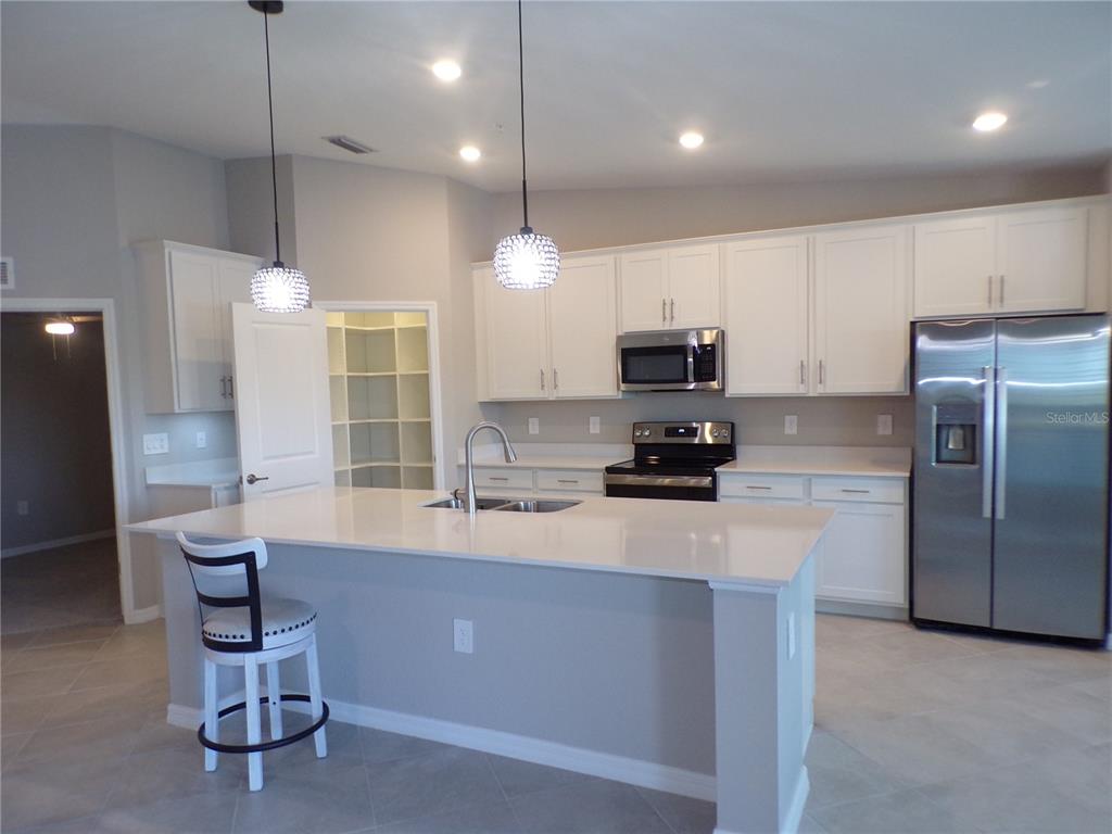 14271 Heritage Landing Boulevard, Unit 1526 Punta Gorda, FL 33955 - Photo 22 of 41 a kitchen with granite countertop a refrigerator a stove a sink a dining table and chairs