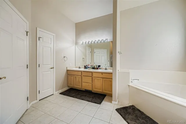 a bathroom with a double vanity sink a mirror and a bathtub