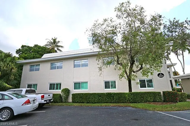 a view of a white house with a large tree