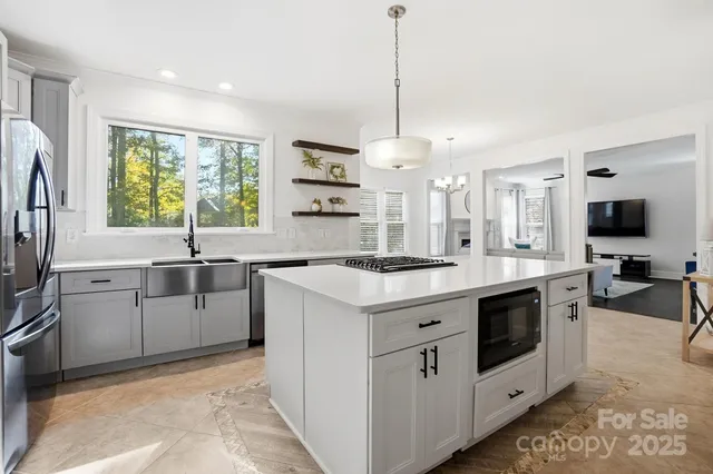 a kitchen that has a lot of white cabinets and stainless steel appliances