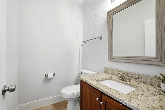 a bathroom with a granite countertop sink toilet and mirror