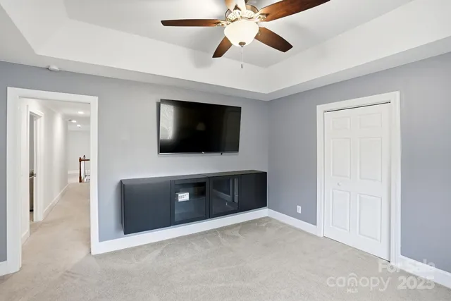a living room with flat screen tv and ceiling fan