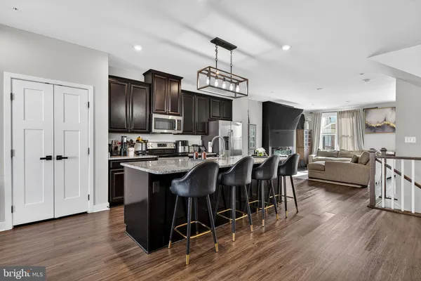 a kitchen with stainless steel appliances a dining table chairs stove refrigerator and cabinets