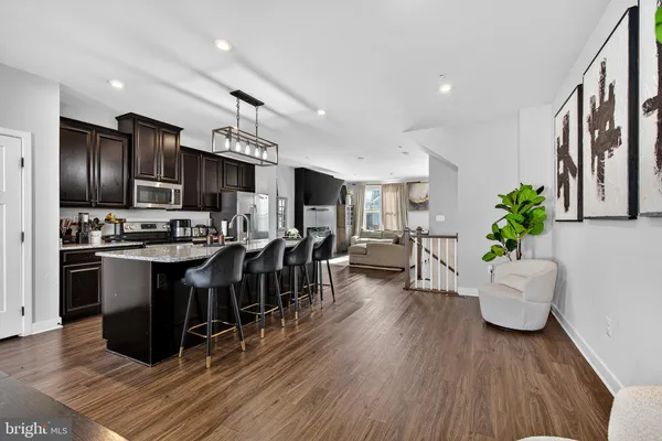a kitchen with stainless steel appliances kitchen island granite countertop wooden floors and a view of living room
