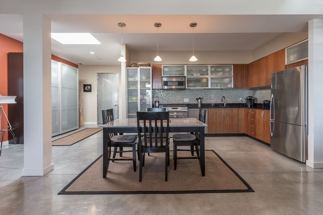 a kitchen with stainless steel appliances granite countertop table chairs sink and cabinets