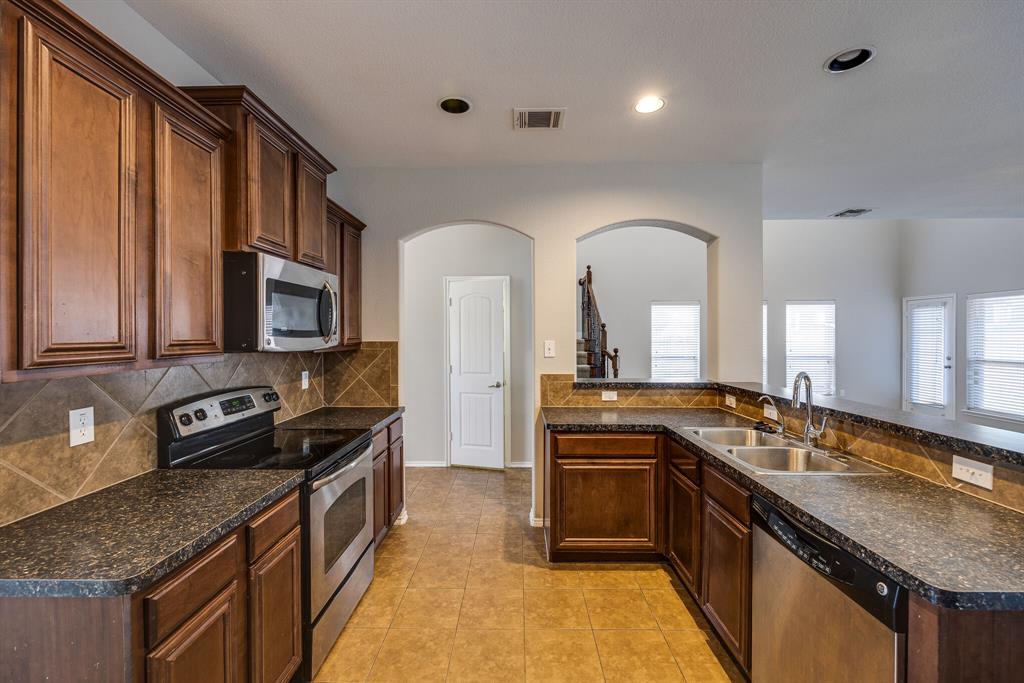 2228 Canyon Point McKinney, TX 75071 - Photo 13 of 40 a kitchen with granite countertop stainless steel appliances a sink stove top oven and cabinets