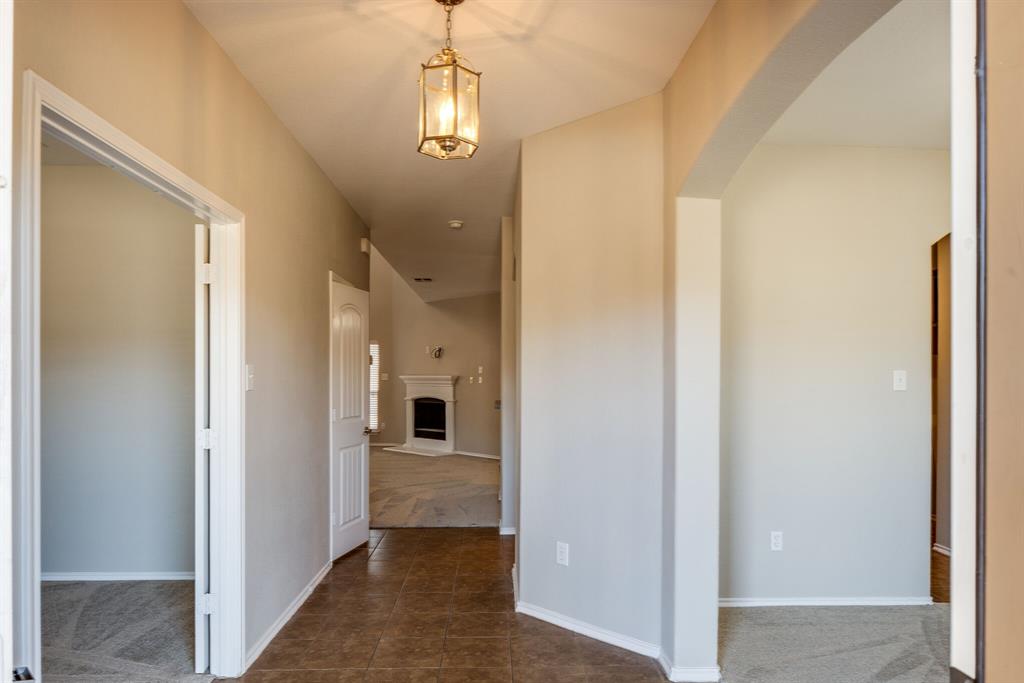 2228 Canyon Point McKinney, TX 75071 - Photo 5 of 40 a view of a hallway with a dining table and chandelier