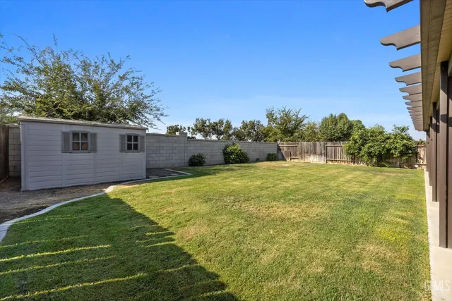 a view of a backyard with plants and large trees
