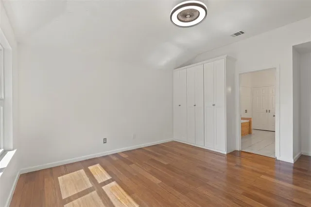 a view of empty room with wooden floor and fan