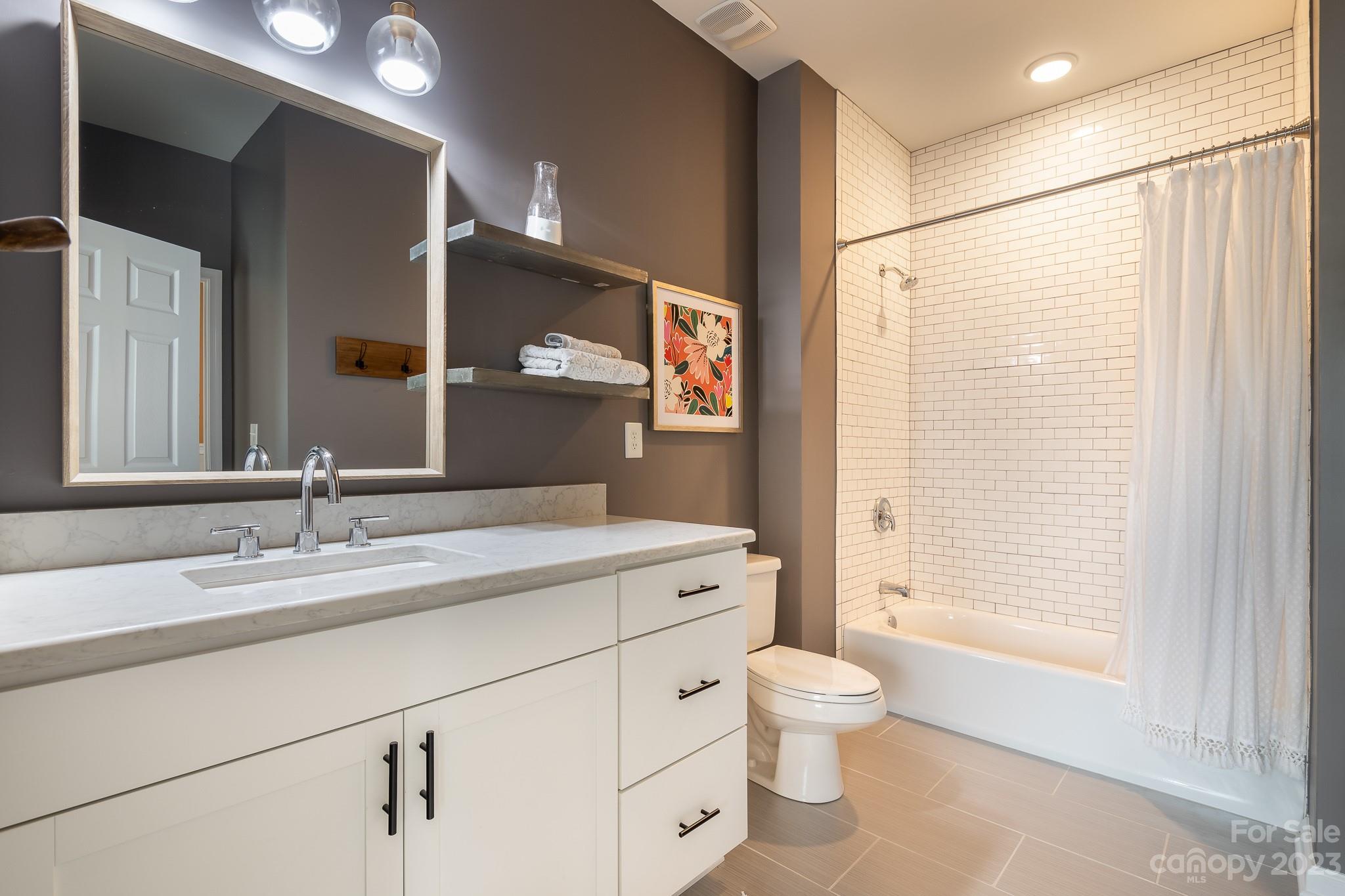 725 Naramore Street Davidson, NC 28036 - Photo 18 of 27 a bathroom with a granite countertop sink toilet a large mirror a shower and a bathtub