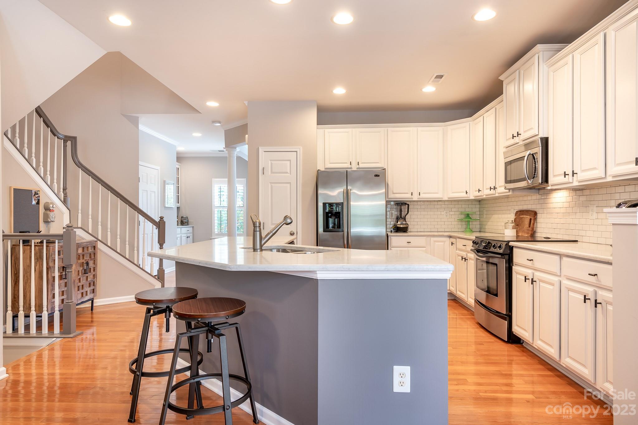 725 Naramore Street Davidson, NC 28036 - Photo 4 of 27 a kitchen with stainless steel appliances granite countertop a stove top oven a sink a refrigerator and white cabinets with wooden floor