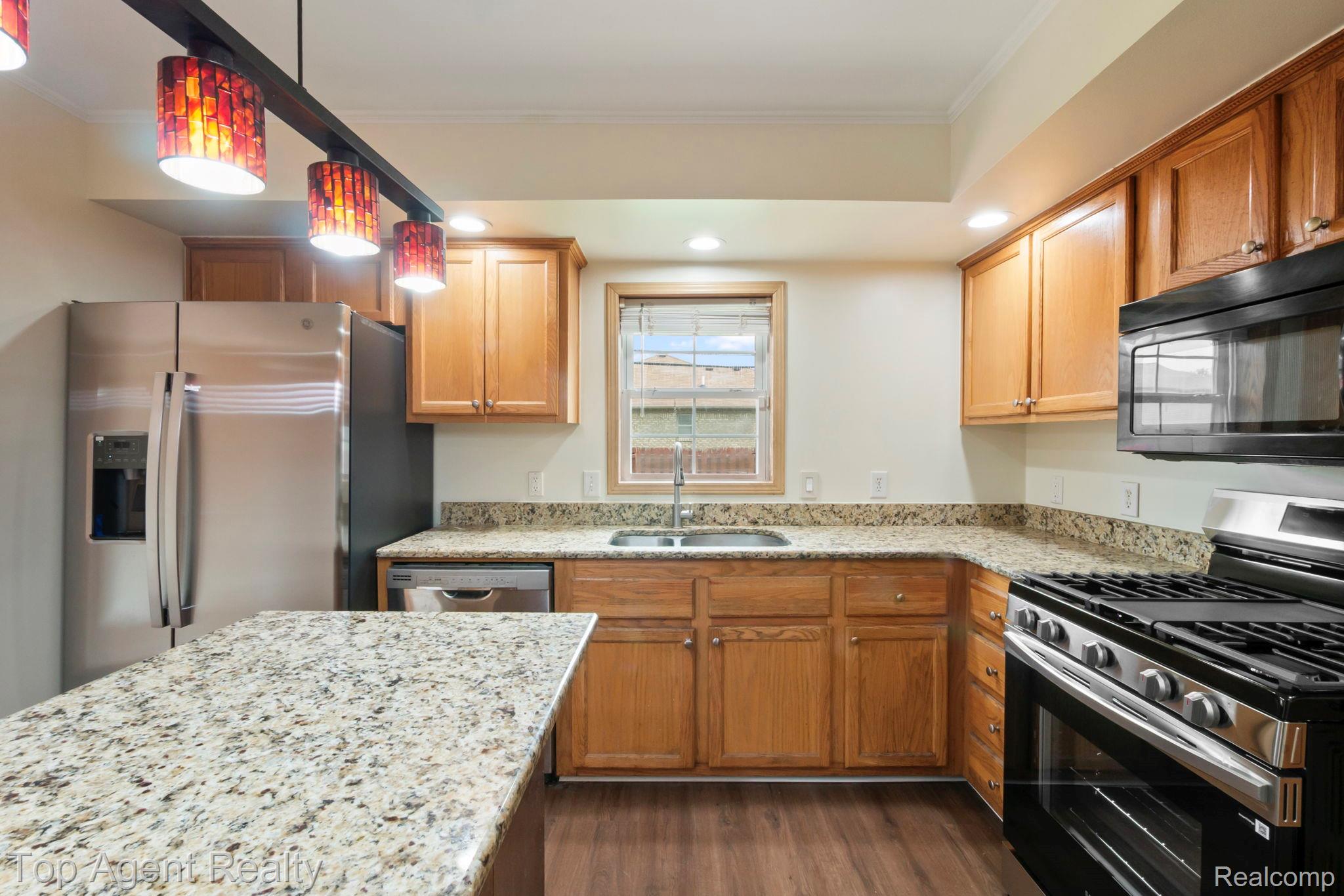 2018 John R Road Troy, MI 48083 - Photo 5 of 30 Kitchen with stainless steel appliances, light stone countertops, decorative light fixtures, dark wood finished floors, and crown molding