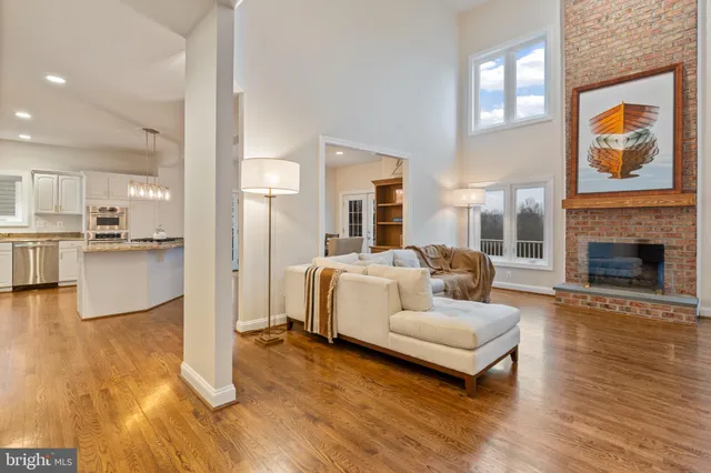 a open kitchen with stainless steel appliances granite countertop a stove top oven a sink a dining table and chairs with wooden floor