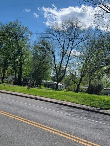 a green field with lots of trees in the background