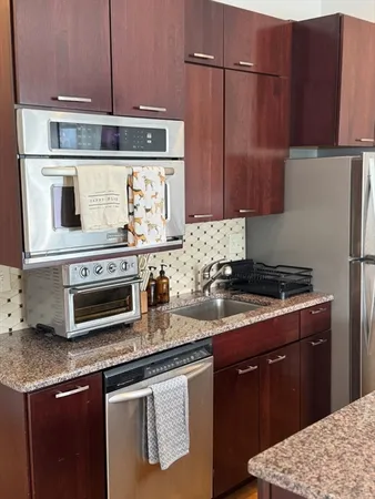 a kitchen with stainless steel appliances granite countertop a stove a sink and a microwave