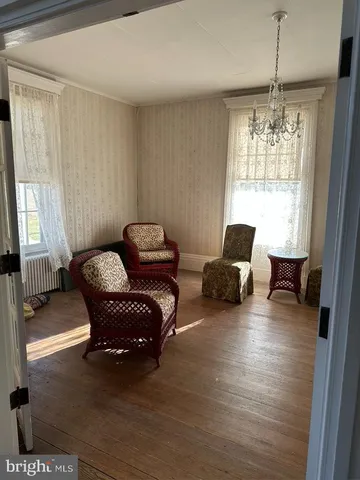 an empty room with wooden floor fireplace cabinet and windows