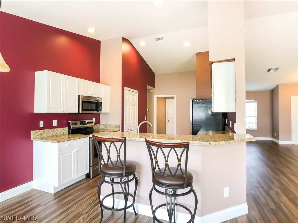 9068 Morris Road Fort Myers, FL 33967 - Photo 10 of 29 a kitchen with stainless steel appliances kitchen island granite countertop a table chairs and a refrigerator