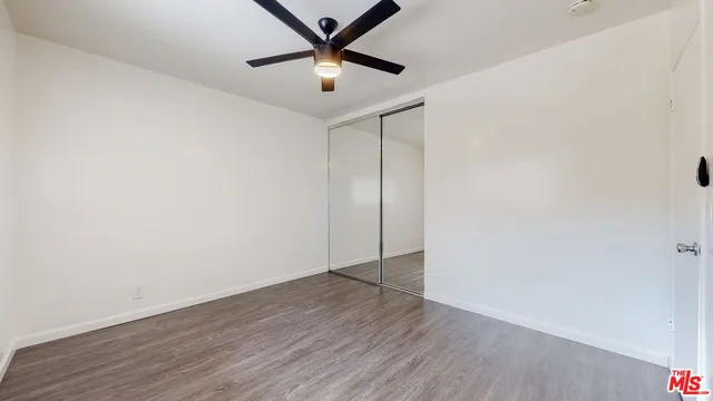 an empty room with wooden floor and a ceiling fan