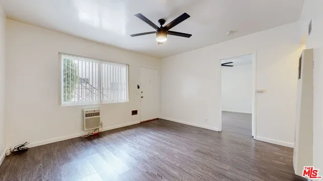 an empty room with wooden floor a ceiling fan and windows
