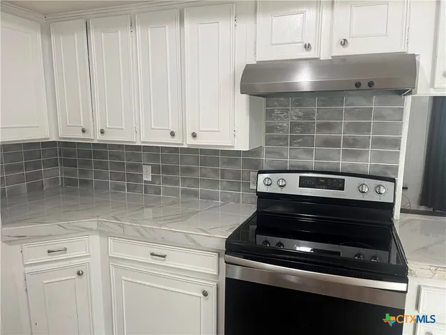 a kitchen with a stove and white cabinets