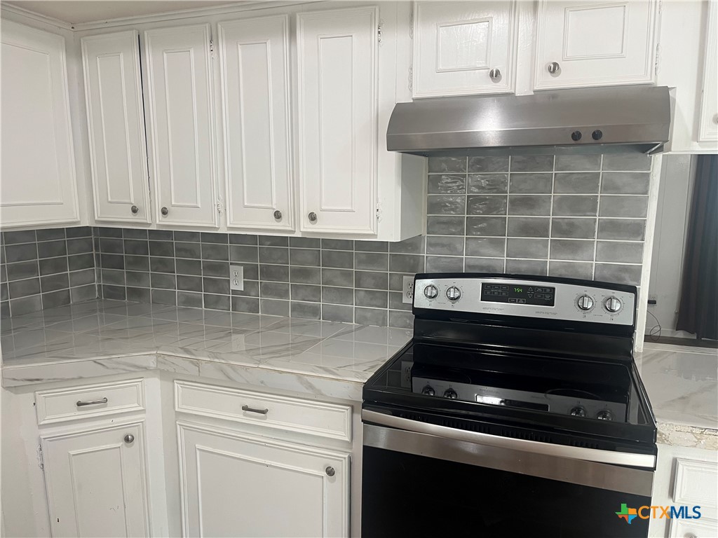 2603 West Main Street Cameron, TX 76520 - Photo 12 of 26 a kitchen with a stove and white cabinets
