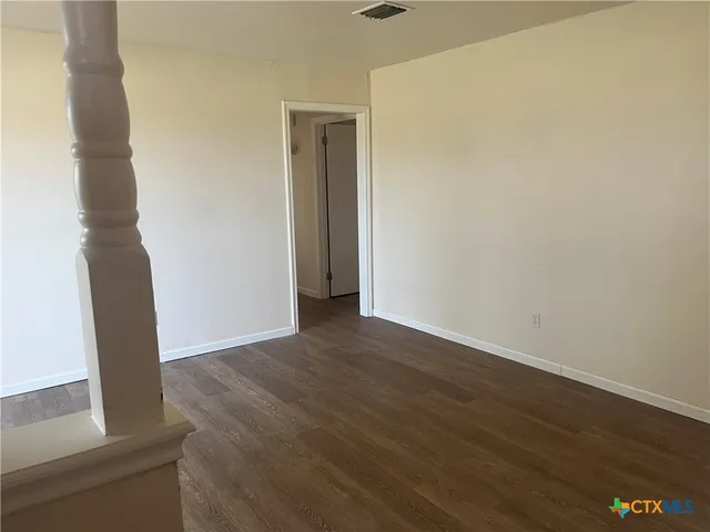 an empty room with wooden floor and entrance