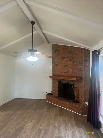 an empty room with wooden floor fireplace and staircase