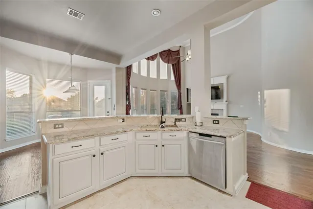 a large white kitchen with a sink large window and cabinets
