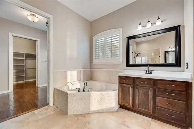 a bathroom with a tub double sink window and mirror