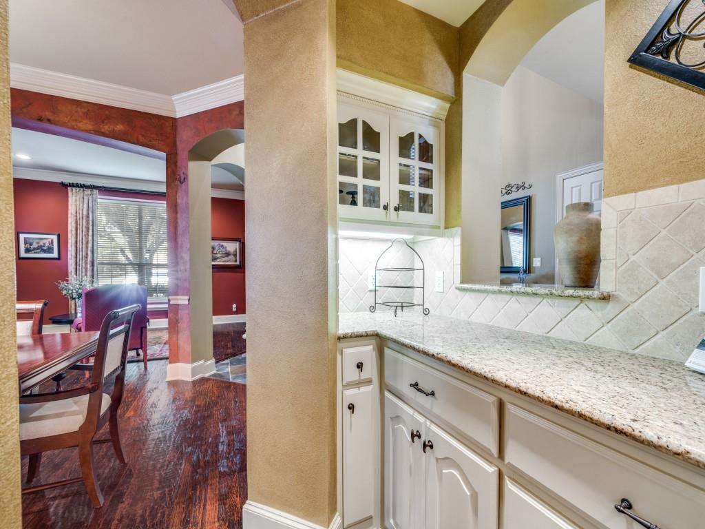 6470 Hunters Parkway Frisco, TX 75035 - Photo 17 of 40 Bar area with arched walkways, light stone countertops, dark wood-type flooring, glass insert cabinets, and tasteful backsplash