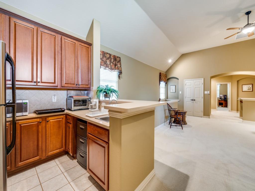 6470 Hunters Parkway Frisco, TX 75035 - Photo 25 of 40 Kitchen featuring brown cabinetry, arched walkways, a peninsula, lofted ceiling, and light colored carpet
