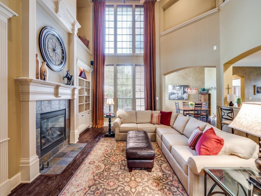 6470 Hunters Parkway Frisco, TX 75035 - Photo 3 of 40 Living room featuring arched walkways, a towering ceiling, a tiled fireplace, and wood finished floors
