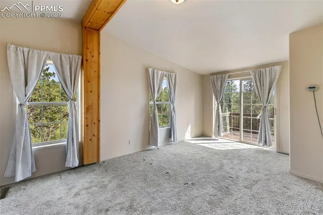 a view of an empty room with a window and bathroom