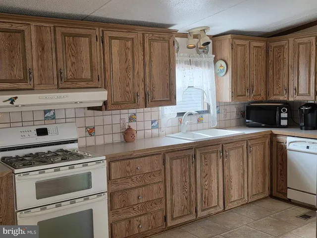 a kitchen with stainless steel appliances granite countertop a sink a stove and cabinets