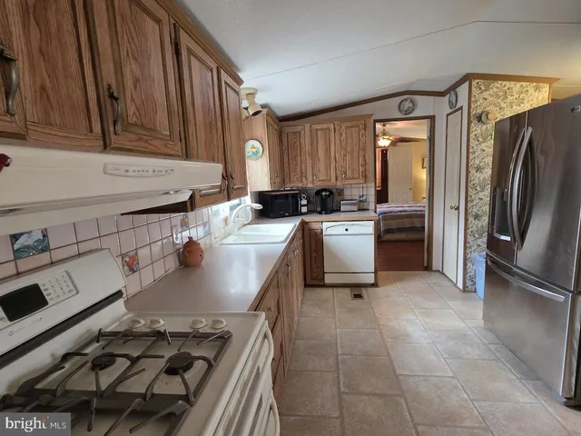 a kitchen with stainless steel appliances a sink a stove a refrigerator cabinets and a window