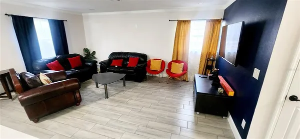 a living room with furniture a flat screen tv and a window