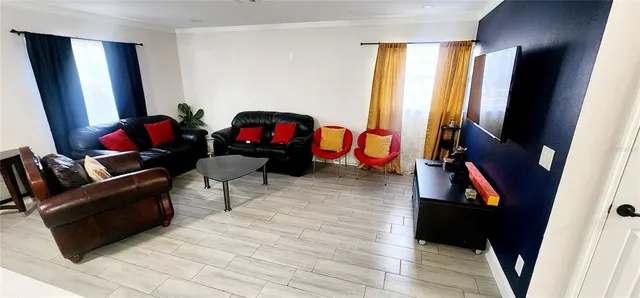 a living room with furniture a flat screen tv and a window