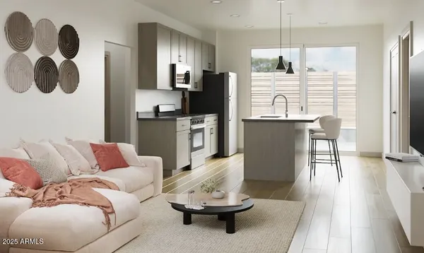 a living room with stainless steel appliances furniture and a kitchen view