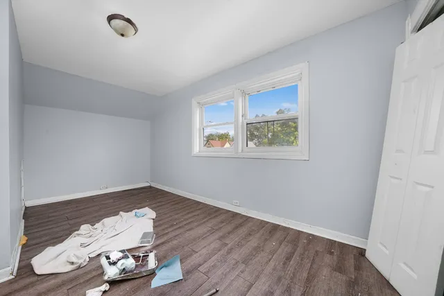 an empty room with wooden floor and window