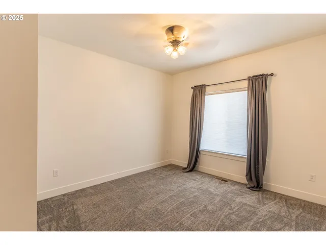 a view of an empty room with closet and a window