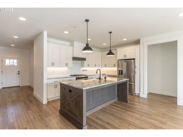 a kitchen with kitchen island a counter top space a sink refrigerator and cabinets