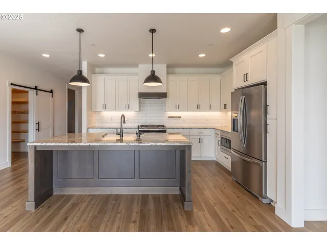 a kitchen with stainless steel appliances granite countertop a sink a stove a refrigerator and a wooden floor