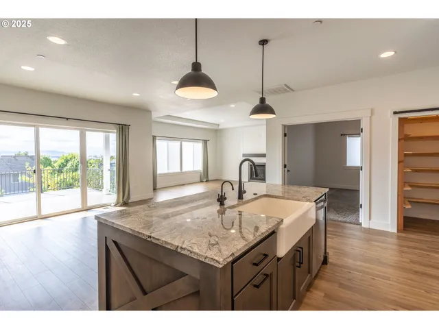 a kitchen with stainless steel appliances granite countertop a sink a stove and a wooden floors